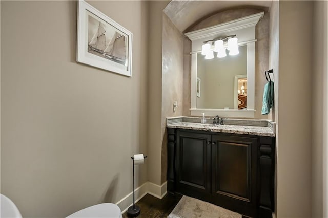 15601 Windsor St, Overland Park, KS 66224 - half bathroom with toilet, vanity, baseboards, and wood finished floors
