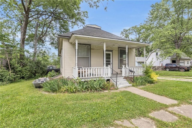 view of front of property featuring a porch, a front lawn, and roof with shingles