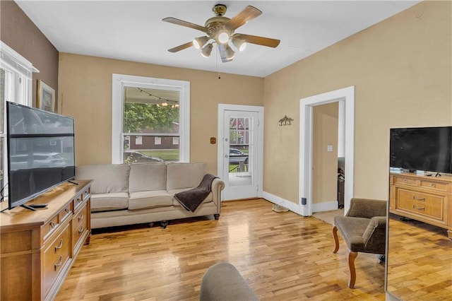living area featuring light wood finished floors, ceiling fan, and baseboards