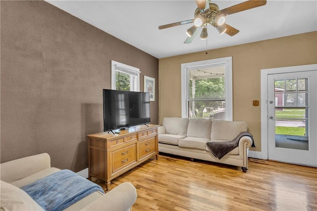 living room with plenty of natural light, light wood finished floors, and ceiling fan