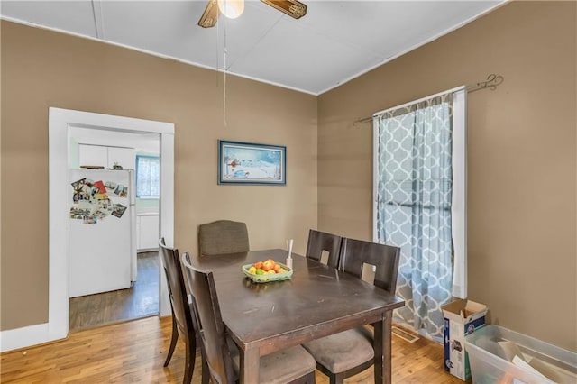 dining area featuring light wood-style flooring, ceiling fan, and baseboards