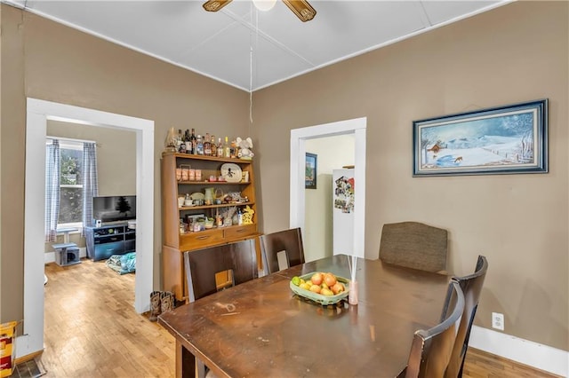 dining space with wood finished floors, a ceiling fan, and baseboards