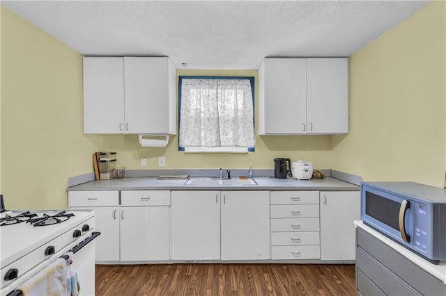 kitchen featuring a sink, white appliances, light countertops, white cabinetry, and dark wood-style flooring