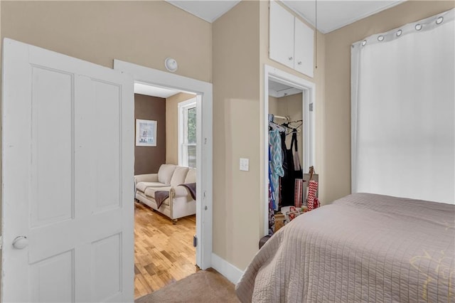 bedroom featuring light wood-type flooring, baseboards, a closet, and a spacious closet