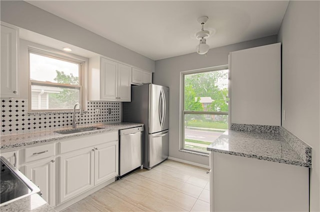 9406 Switzer St, Overland Park, KS 66214 - kitchen with appliances with stainless steel finishes, a sink, white cabinetry, decorative backsplash, and healthy amount of natural light