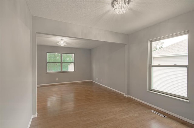 9406 Switzer St, Overland Park, KS 66214 - spare room featuring a chandelier, wood finished floors, baseboards, and a textured ceiling