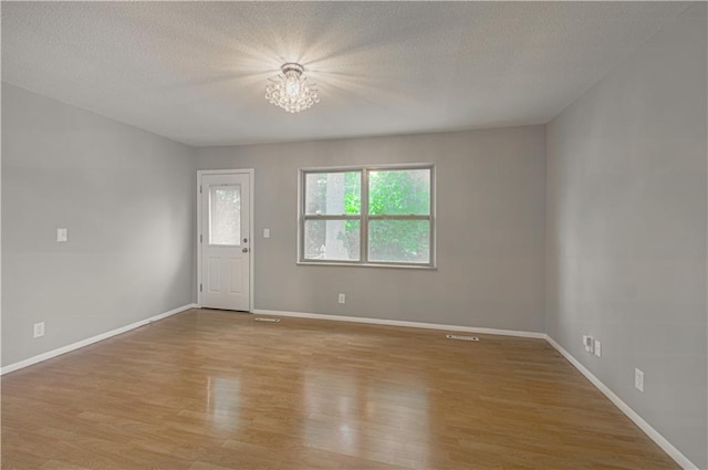 9406 Switzer St, Overland Park, KS 66214 - spare room featuring light wood-style floors, a chandelier, a textured ceiling, and baseboards