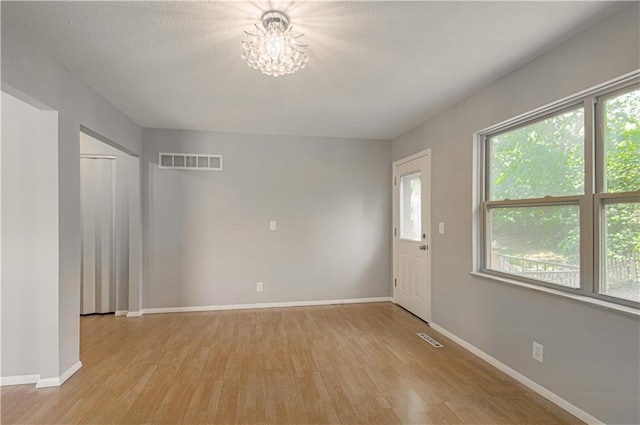 9406 Switzer St, Overland Park, KS 66214 - unfurnished room featuring light wood-type flooring, a chandelier, healthy amount of natural light, and baseboards