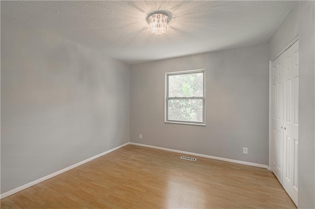 9406 Switzer St, Overland Park, KS 66214 - unfurnished bedroom featuring a chandelier, light wood finished floors, a closet, baseboards, and a textured ceiling