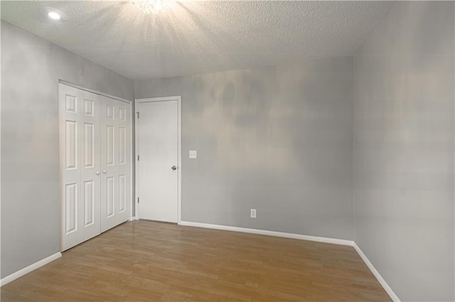 9406 Switzer St, Overland Park, KS 66214 - unfurnished bedroom featuring light wood-style flooring, baseboards, a textured ceiling, a closet, and recessed lighting