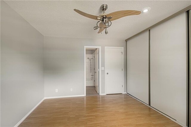 9406 Switzer St, Overland Park, KS 66214 - unfurnished bedroom with a textured ceiling, light wood-style flooring, a closet, baseboards, and connected bathroom
