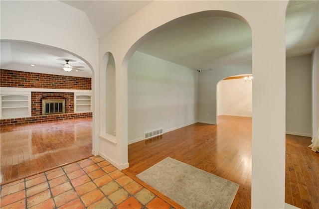 1014 SW Twilight Ln, Blue Springs, MO 64015 - foyer entrance with a ceiling fan, arched walkways, lofted ceiling, wood finished floors, and a brick fireplace