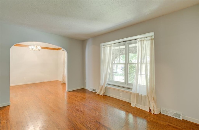 1014 SW Twilight Ln, Blue Springs, MO 64015 - unfurnished room with arched walkways, wood finished floors, a chandelier, and a textured ceiling