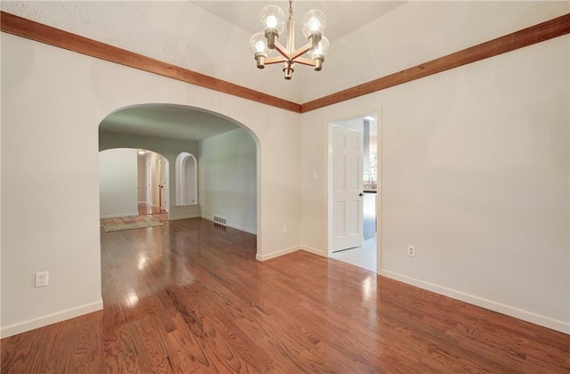1014 SW Twilight Ln, Blue Springs, MO 64015 - spare room with arched walkways, wood finished floors, a chandelier, and lofted ceiling