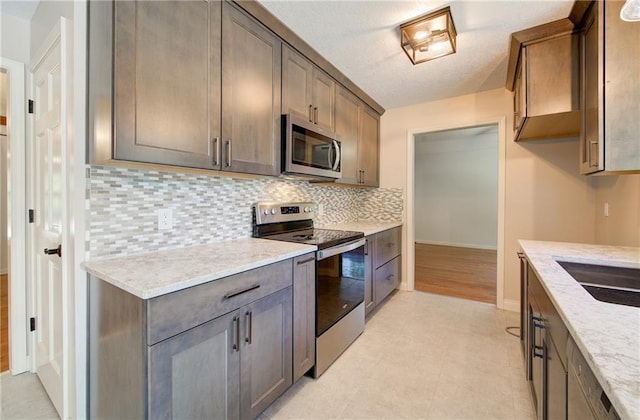 1014 SW Twilight Ln, Blue Springs, MO 64015 - kitchen featuring appliances with stainless steel finishes, decorative backsplash, light stone countertops, and a textured ceiling