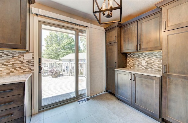 1014 SW Twilight Ln, Blue Springs, MO 64015 - kitchen with a chandelier, decorative backsplash, light tile patterned floors, and light stone counters