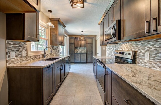 1014 SW Twilight Ln, Blue Springs, MO 64015 - kitchen featuring appliances with stainless steel finishes, backsplash, dark brown cabinetry, pendant lighting, and light stone countertops