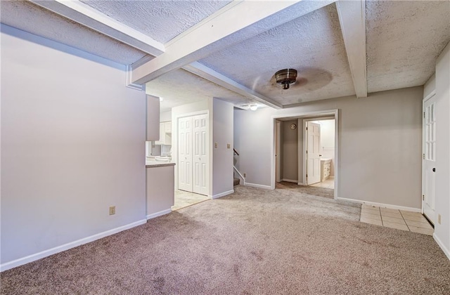 1014 SW Twilight Ln, Blue Springs, MO 64015 - spare room with light colored carpet, beam ceiling, stairs, and a textured ceiling