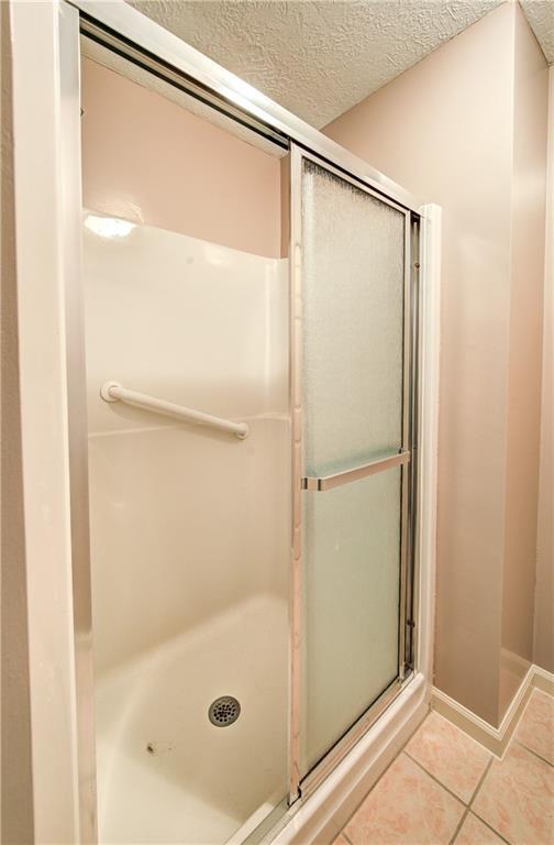 1014 SW Twilight Ln, Blue Springs, MO 64015 - full bath featuring tile patterned floors, a shower stall, and a textured ceiling