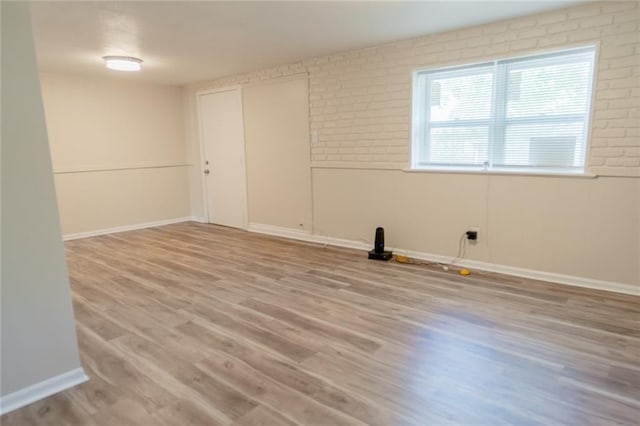 10203 Fremont Ave, Kansas City, MO 64134 - empty room with light wood finished floors, baseboards, and brick wall