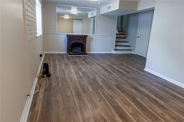 10203 Fremont Ave, Kansas City, MO 64134 - unfurnished living room featuring stairs, baseboards, wood finished floors, and a fireplace