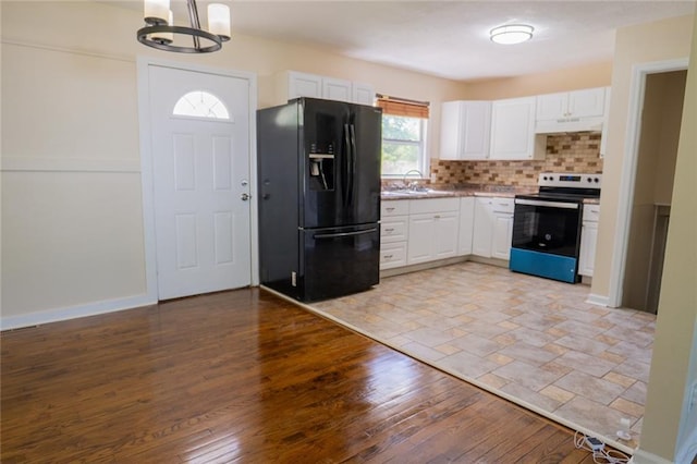 10203 Fremont Ave, Kansas City, MO 64134 - kitchen with black refrigerator with ice dispenser, stainless steel electric range oven, white cabinets, a chandelier, and tasteful backsplash