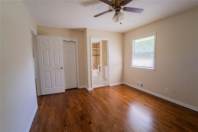 10203 Fremont Ave, Kansas City, MO 64134 - unfurnished bedroom with baseboards, dark wood finished floors, a textured ceiling, connected bathroom, and ceiling fan