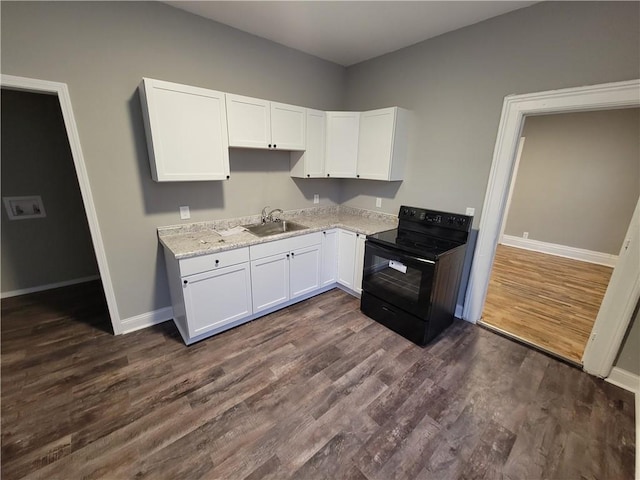 kitchen featuring black electric range oven, a sink, baseboards, and white cabinetry