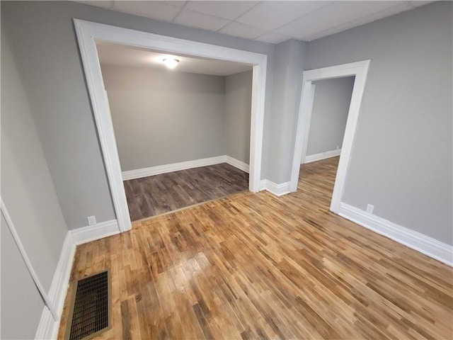 empty room with wood finished floors, baseboards, and a paneled ceiling