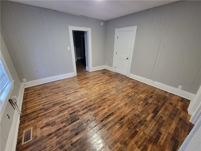 spare room with hardwood / wood-style floors, baseboards, and wooden walls