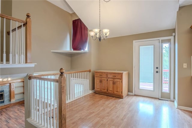 1703 Rolling Rock Rd, Raymore, MO 64083 - entryway featuring healthy amount of natural light, light wood finished floors, a chandelier, lofted ceiling, and a fireplace