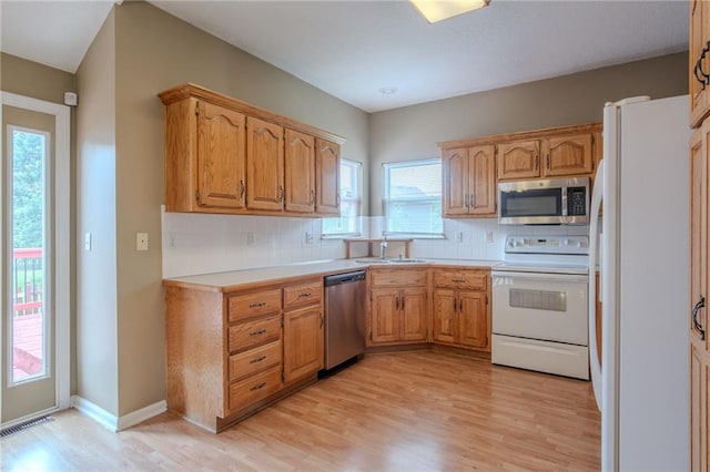 1703 Rolling Rock Rd, Raymore, MO 64083 - kitchen featuring appliances with stainless steel finishes, light wood-type flooring, decorative backsplash, and light countertops