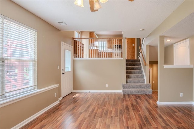 1703 Rolling Rock Rd, Raymore, MO 64083 - unfurnished living room with wood finished floors, stairs, a ceiling fan, and a textured ceiling