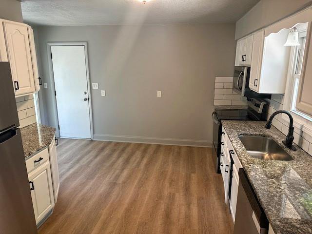 307 SW Glendana St, Lees Summit, MO 64081 - kitchen with stainless steel appliances, a sink, decorative backsplash, light wood-type flooring, and dark stone countertops