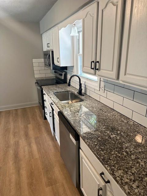 307 SW Glendana St, Lees Summit, MO 64081 - kitchen with appliances with stainless steel finishes, a sink, white cabinets, and wood finished floors