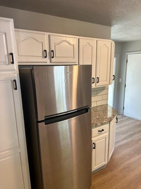 307 SW Glendana St, Lees Summit, MO 64081 - kitchen with freestanding refrigerator, light wood-style floors, white cabinets, decorative backsplash, and dark stone counters