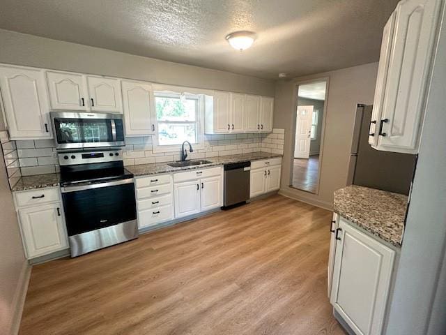 307 SW Glendana St, Lees Summit, MO 64081 - kitchen with stainless steel appliances, a sink, white cabinetry, tasteful backsplash, and a textured ceiling