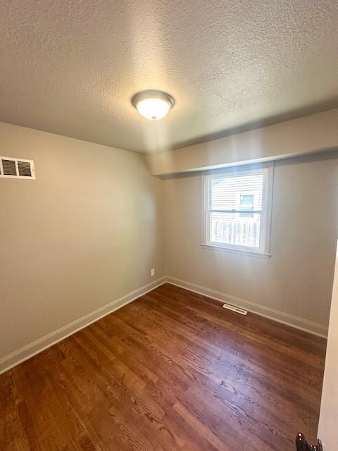 307 SW Glendana St, Lees Summit, MO 64081 - empty room featuring a textured ceiling, dark wood-style flooring, and baseboards