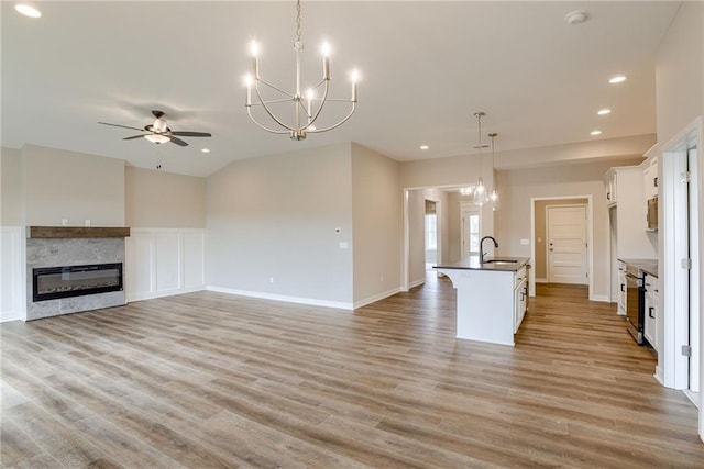 kitchen featuring open floor plan, dark countertops, a sink, a ceiling fan, and light wood finished floors