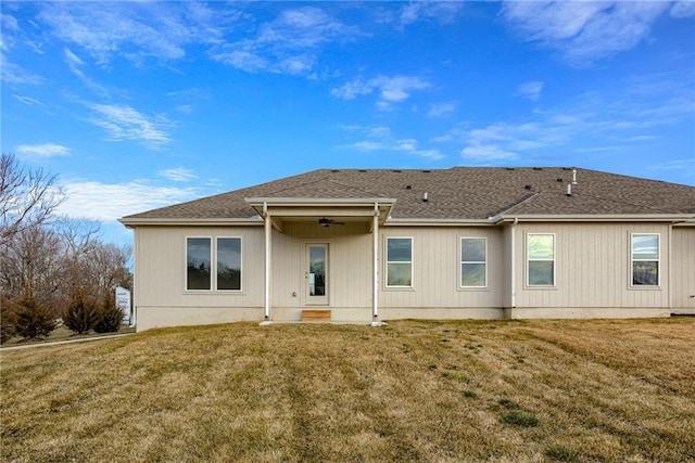 back of property with a ceiling fan, a yard, and roof with shingles