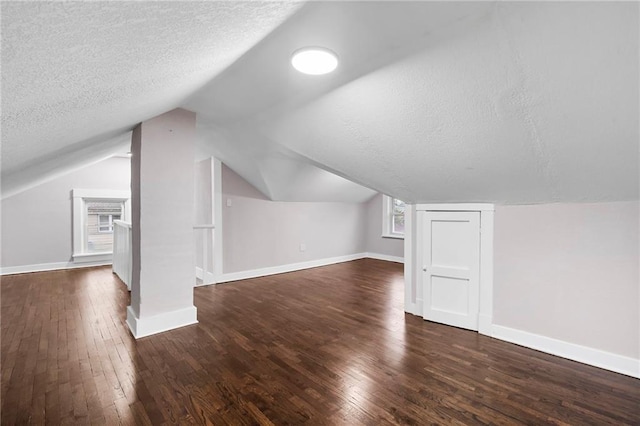 312 2nd St, Ferrelview, MO 64163 - additional living space with a textured ceiling, dark wood-type flooring, lofted ceiling, and baseboards