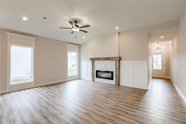 unfurnished living room featuring light wood-style floors, a premium fireplace, a ceiling fan, recessed lighting, and a chandelier