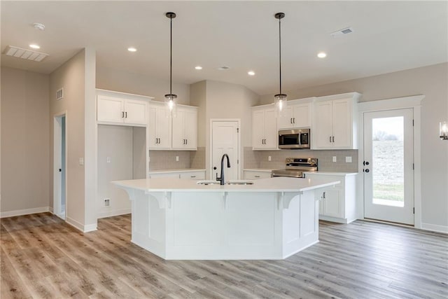 kitchen with appliances with stainless steel finishes, a sink, tasteful backsplash, light countertops, and recessed lighting
