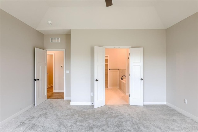 unfurnished bedroom featuring lofted ceiling, carpet flooring, baseboards, and a walk in closet