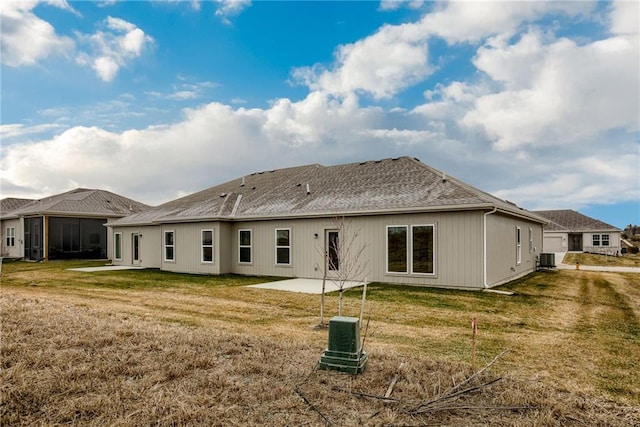 back of property featuring a yard, a patio, central air condition unit, and a shingled roof