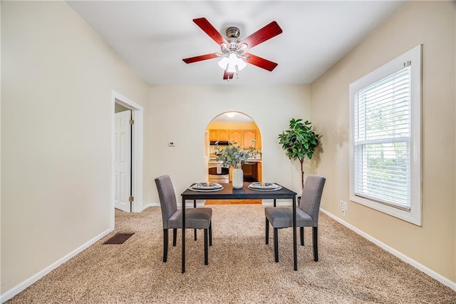 1503 S Spring St, Independence, MO 64055 - carpeted dining area with arched walkways, ceiling fan, and baseboards
