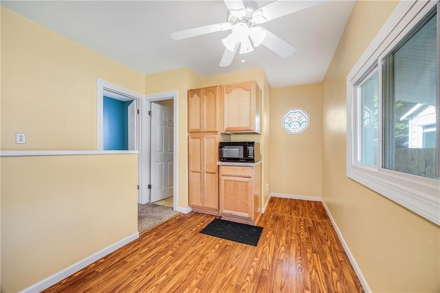 1503 S Spring St, Independence, MO 64055 - kitchen with light brown cabinets, black microwave, baseboards, wood finished floors, and a ceiling fan