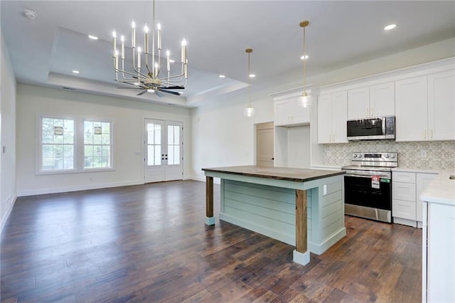 220 Rock Bridge Pkwy, Excelsior Springs, MO 64024 - kitchen with stainless steel appliances, a raised ceiling, backsplash, dark wood-style floors, and white cabinets