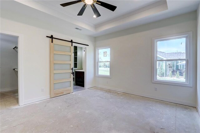 220 Rock Bridge Pkwy, Excelsior Springs, MO 64024 - unfurnished bedroom featuring a barn door, a tray ceiling, crown molding, baseboards, and a spacious closet