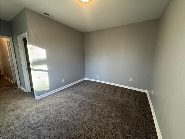 unfurnished room with dark carpet and baseboards